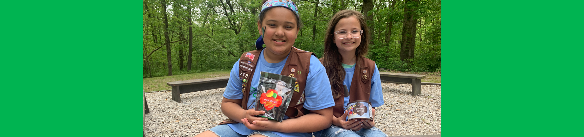  two girl scouts holding fall nut and candy products 