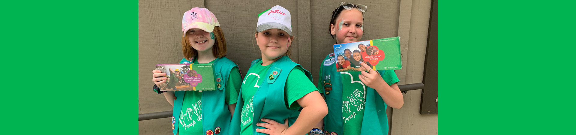  three girl scouts posing with nut and candy products 